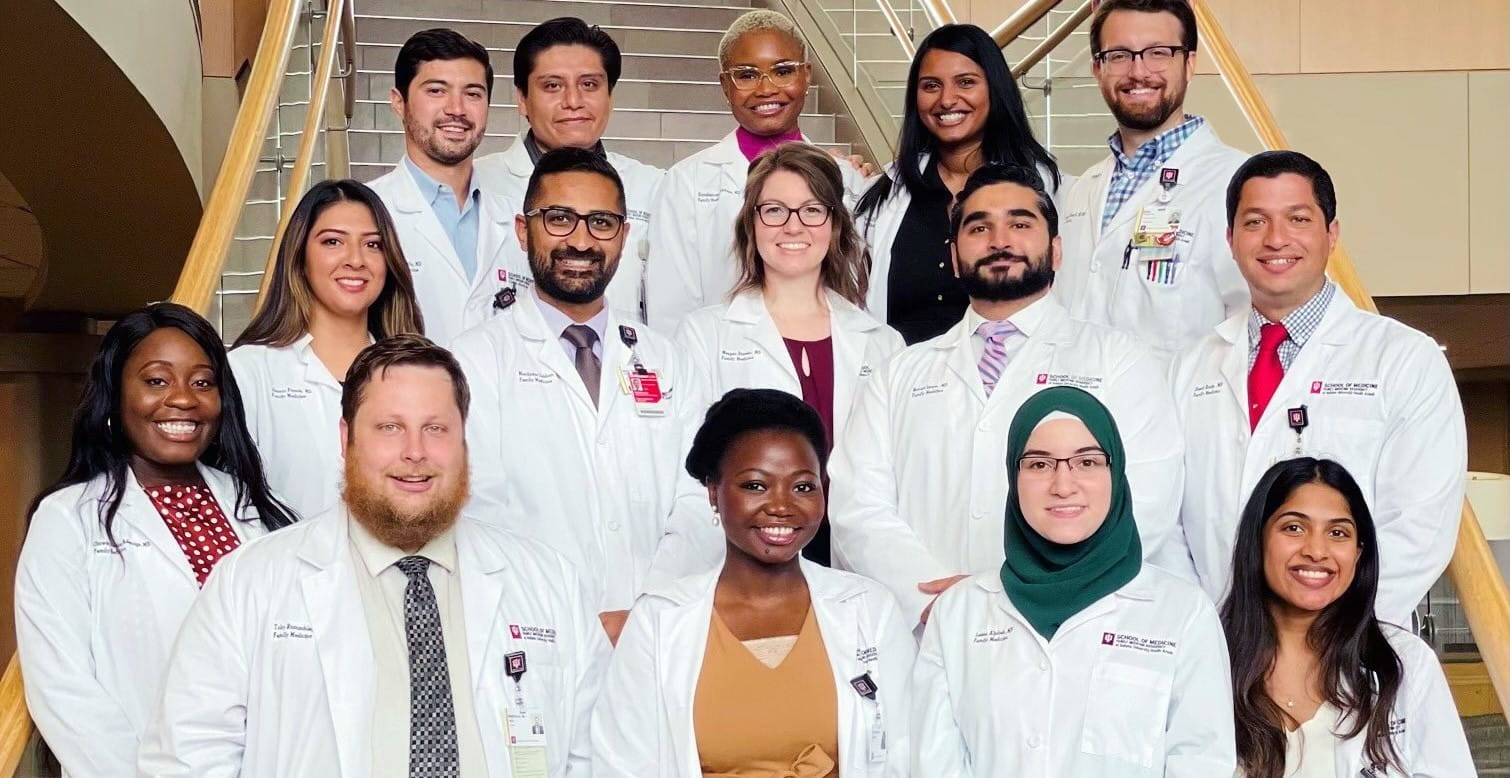 group photo of family medicine residents standing on stairway in white coats