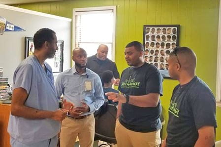 Clark Simons, MD talks with members of Indy HeartBeat at a barbershop