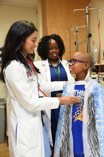 Seethal Jacob, MD, and another faculty physician with a young sickle cell patient
