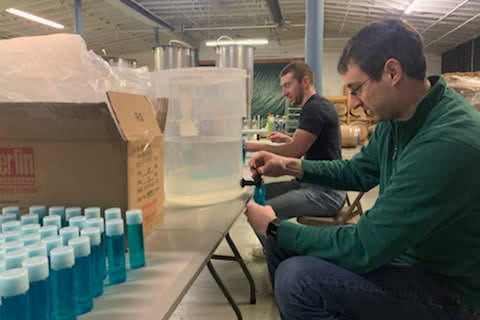 MD students Carl Collins and Vaughn Florian bottle hand sanitizer at Indiana Whiskey Co