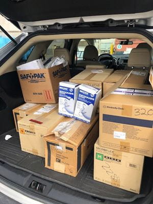 the trunk of an SUV is filled with boxes of PPE