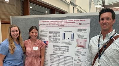 Two medical students and Dr. Brian Gray at 2019 research symposium poster