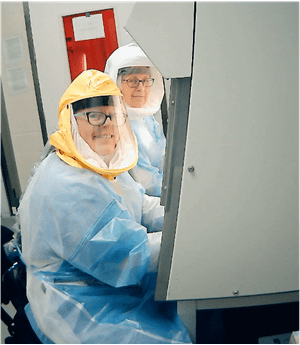 Melissa Kacena and another researcher work while wearing protective coverall suits.