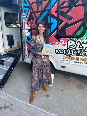 Julia LaMotte selecting a book at the Black Worldschoolers mobile bookstore