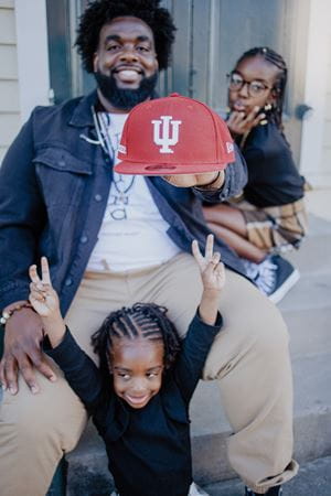 Russell Ledet holding an IU hat with his two girls