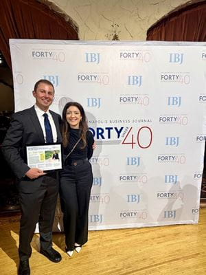 Nabil Adra stands with his wife, Lana Dbeibo, and holds his IBJ award plaque at the IBJ recognition event for 2024 honorees.