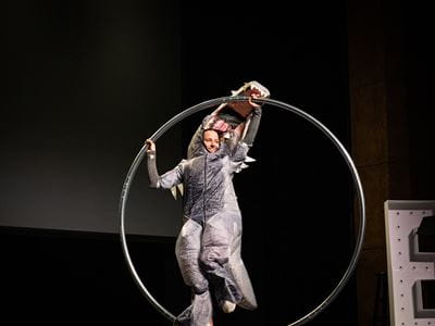 Amanda Thayer in a dinosaur costume performing acrobatics on a Cyr wheel