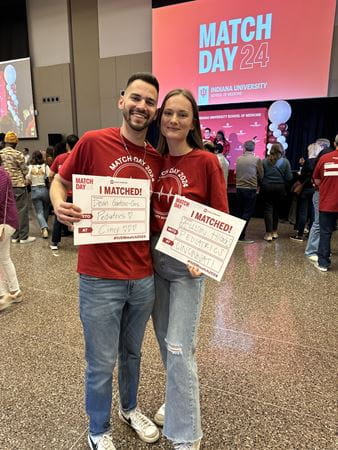 Devin Gantzios-Cros and Allison Higgs stand together holding their Match Day 2024 signs indicating their match into the pediatrics residency at Cincinnati Children's