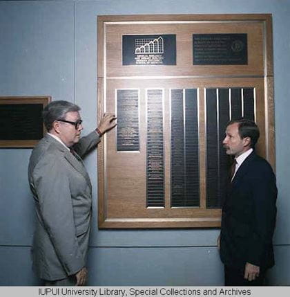 Walter Daly and IUPUI Chancellor Gerald Bepko look at a plaque on the wall in the Medical Research and Library Building