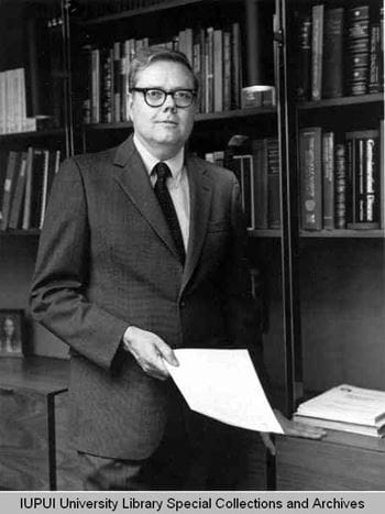 Black and white photo of Walter Daly wearing a suit in a library, taken in 1983