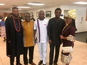 Kola Okuyemi posing with four dark-skinned mentees wearing traditional African dress at a church event
