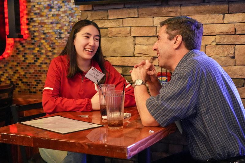 An IU resident talks with a man, sitting together at a table, during the award dinner.