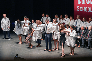 Students on stage receive their white coats from deans and faculty.