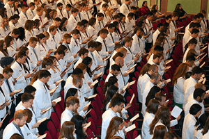 Students at the 2024 White Coat Ceremony stand and recite the Physician's Oath.