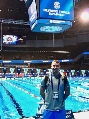 Zach Wagner, DO, stands poolside at Lucas Oil Stadium, wearing his medical team credentials.