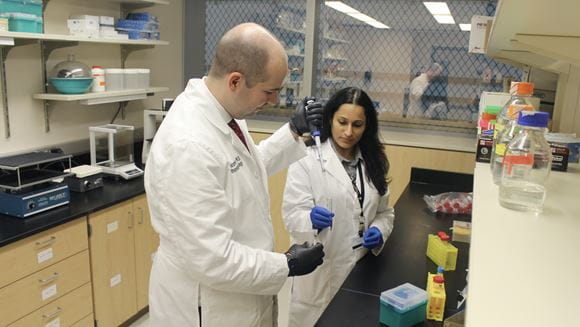 Christopher Collier, MD, works in his lab with laboratory manager Anuradha Valiya Kambrath