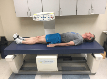 a man lays on a table with a bone density scan machine moving over his body