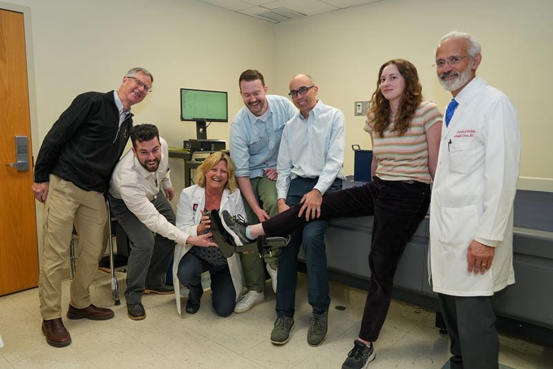 members of the research team laugh as they fit a test device over another team member's leg