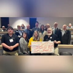 Group photo of Wells Center researchers and Lions club members holding a large donation check