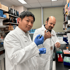 Drs. Tran and Kapur pose with lab equipment