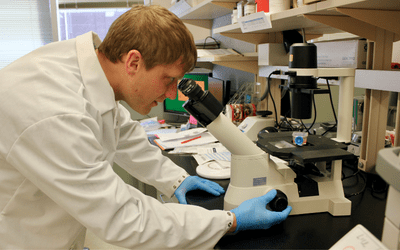 Dan Peltier looking through a microscope in his lab
