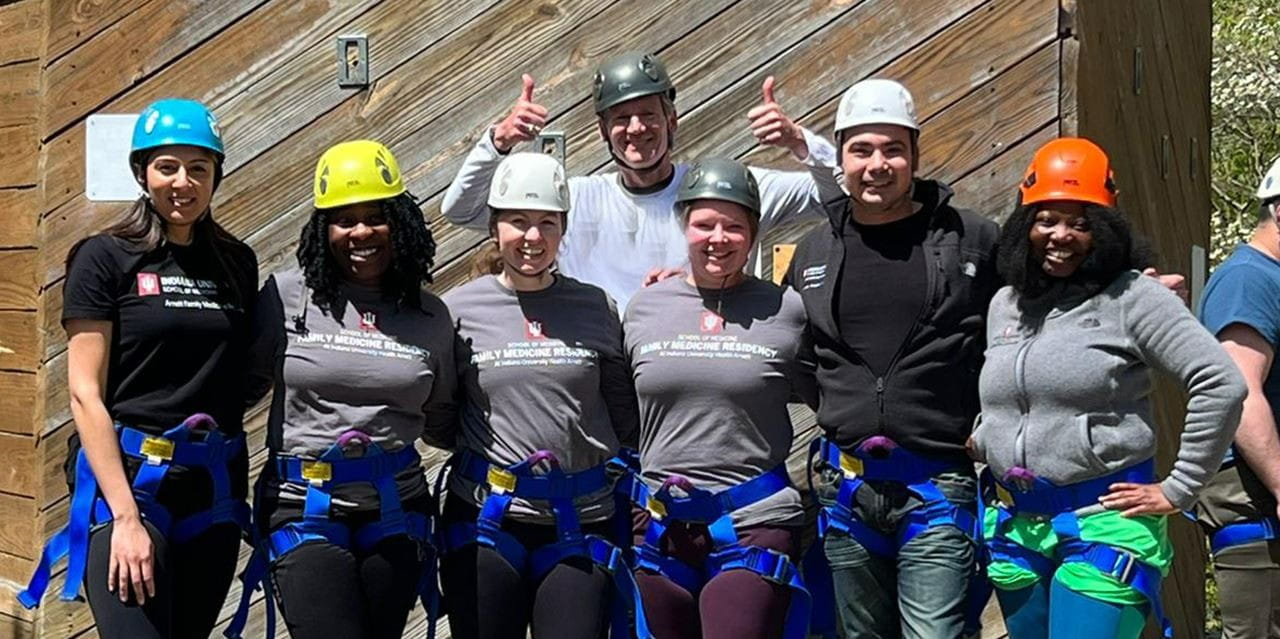 family medicine residents from IU Health Arnett wearing climbing harnesses and helmets at a wellness event