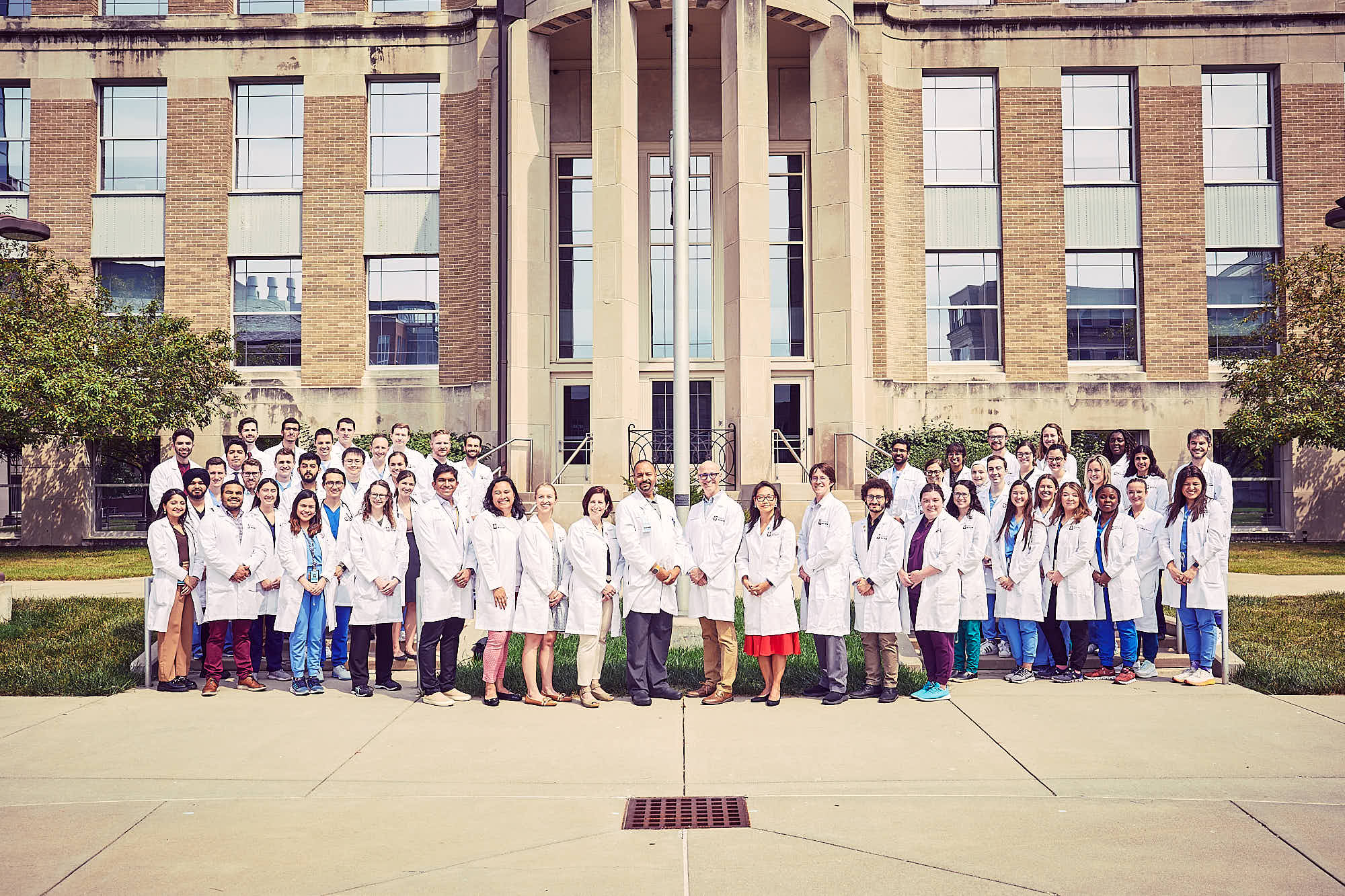 A group of internal medicine residents, chiefs, and leadership gathered in front of a building.