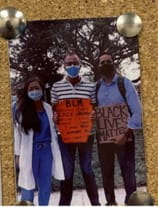 Photo on a bulletin board of three individuals posing together wearing masks
