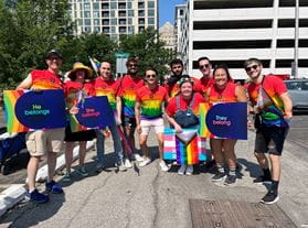 a group of people at the indy pride parade wearing rainbow tie dye shirts holding signs and flags