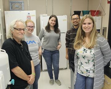 Five members of the Greenfield Lab staff stand in their lab