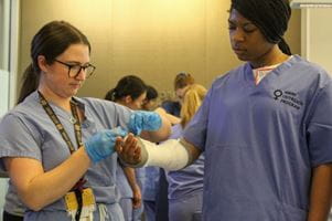 Orthopaedic Surgery Resident Sarah Levey, MD, shows a Perry Initiative student how to properly apply a cast to an arm.
