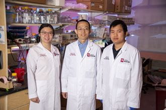 three researchers in the Glick Lab wearing white lab coats