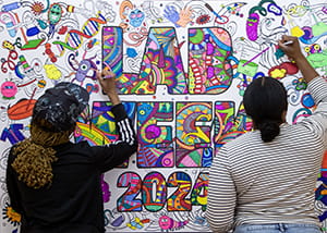 Two people coloring in a poster