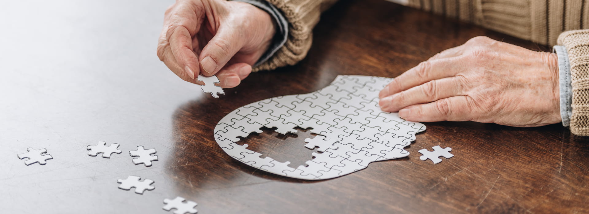 close up of hands putting together a puzzle of a person's head