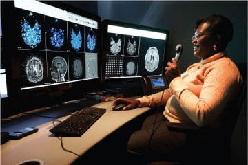 Faith Oguk sitting in front of computer screen looking at scans in a radiology reading room