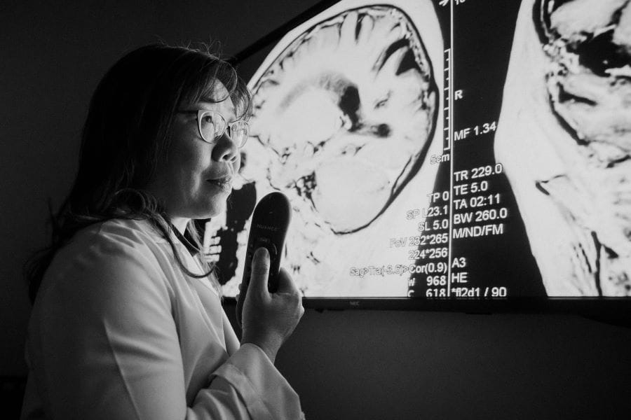 A radiologist working in front of an imaging screen showing a brain