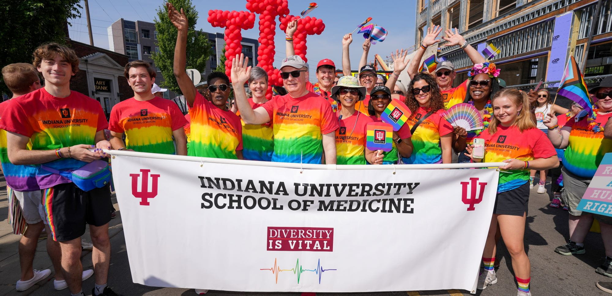 the dean, faculty leaders and students hold a banner and balloons as they march in the 2023 Indy Pride Parade