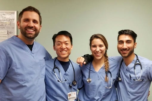 four residents in scrubs with stethoscopes around their necks