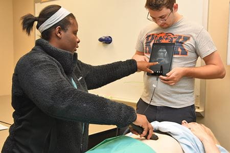 two students practices POCUS with a wand and small tablet