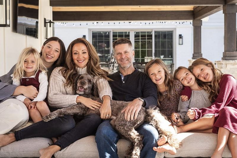 Lindsay Weaver and her husband sit in the center of a large couch, surrounded by their five children and family dog.