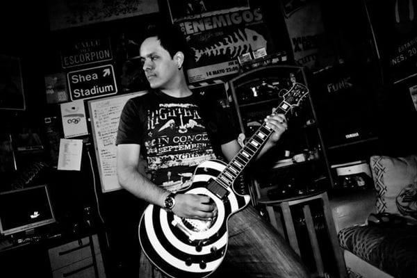 rodolfo gonzalez shreds on a striped guitar in a black and white photo