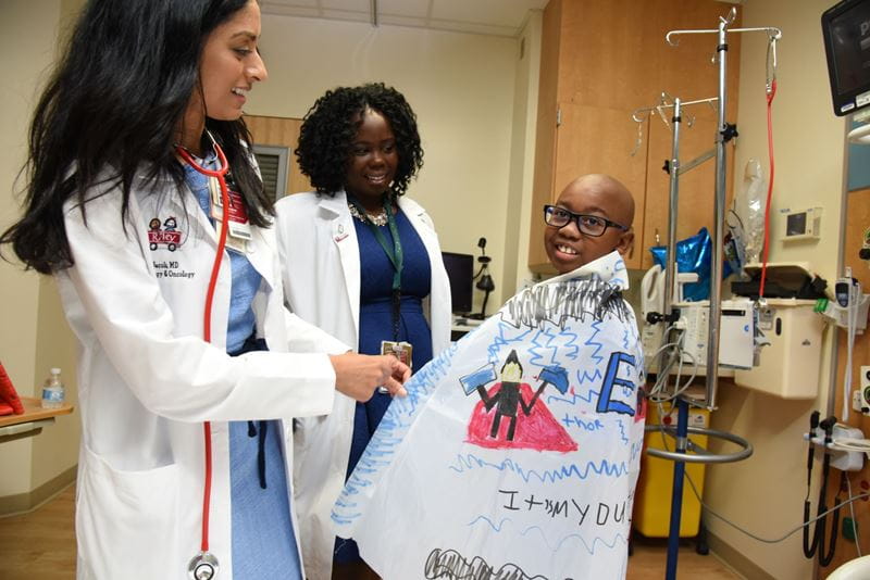 Seethal Jacob and another physician speak with a young patient with sickle cell disease