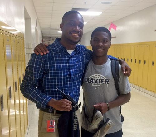 myke spencer and a student stand with their arms around each other in a school hallway