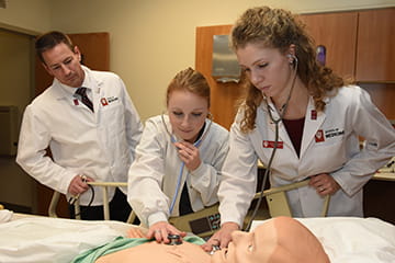students examine a medical dummy in a simulation class