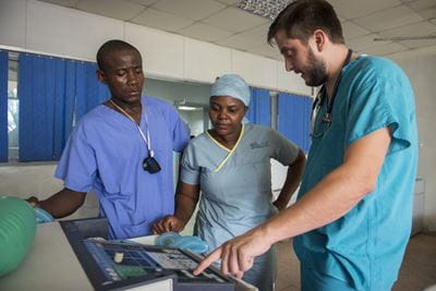 An image of Dr. Michael Davis in a clinic with two people dressed in scrubs.
