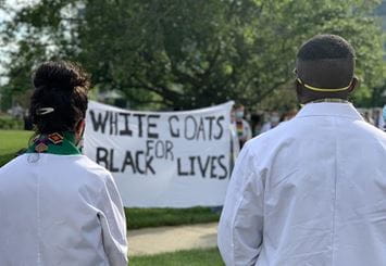 medical students looking at White Coats for Black Lives banner 